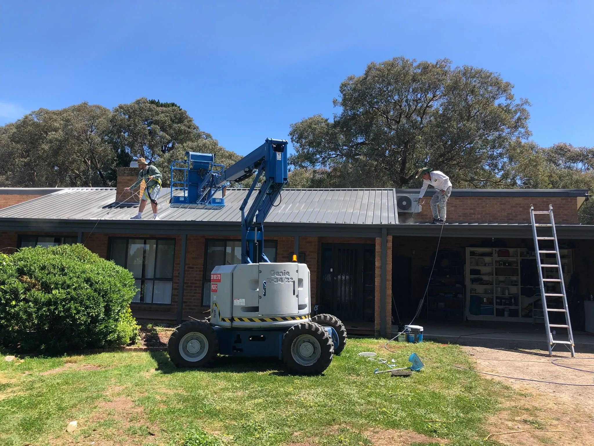 A boom lift beside a one-story brick house