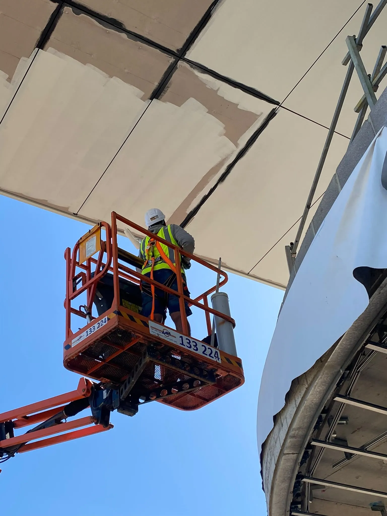 Two painters in a boom lift under a curved soffit