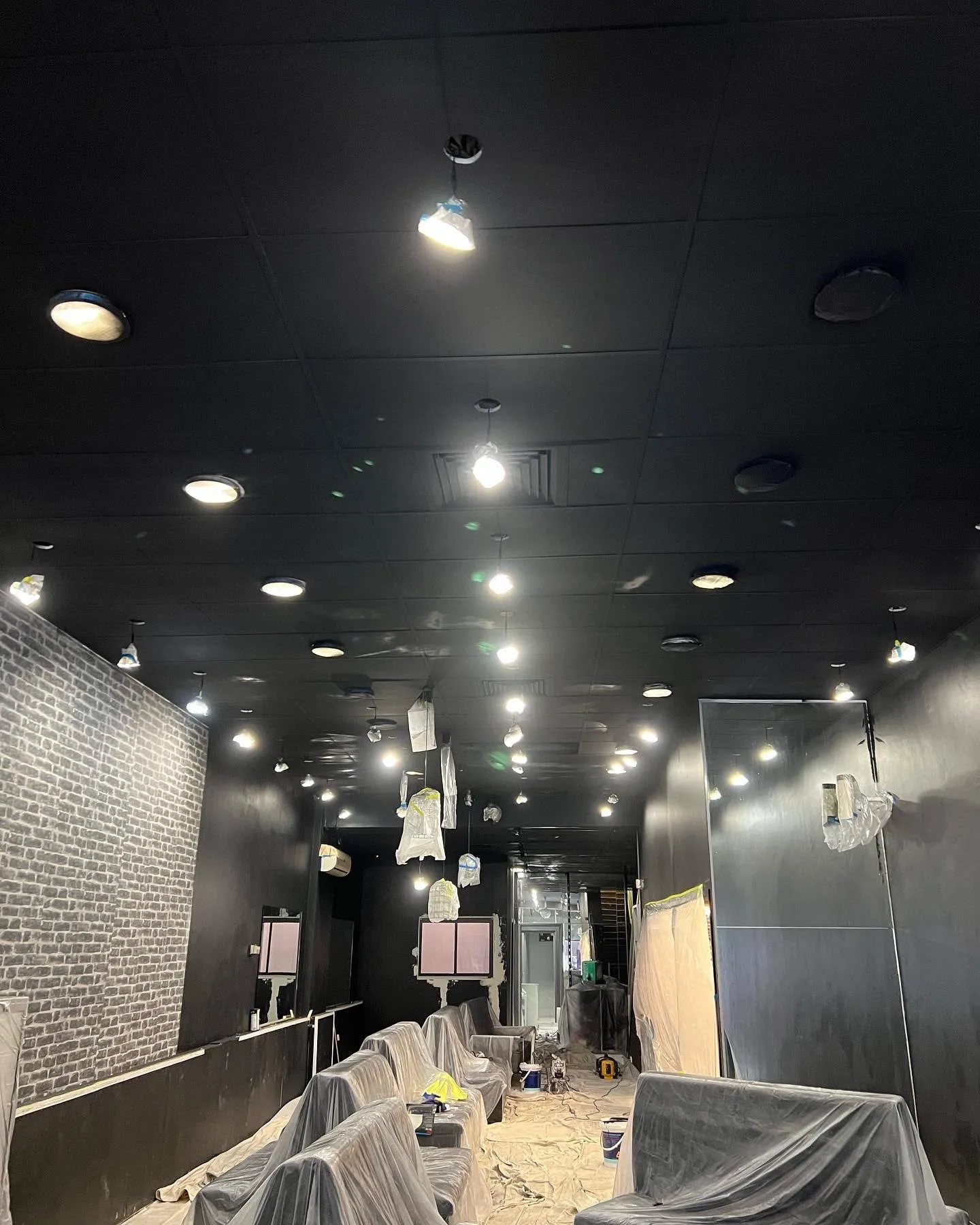 A sprayed black ceiling above a bar, with the seating covered in plastic