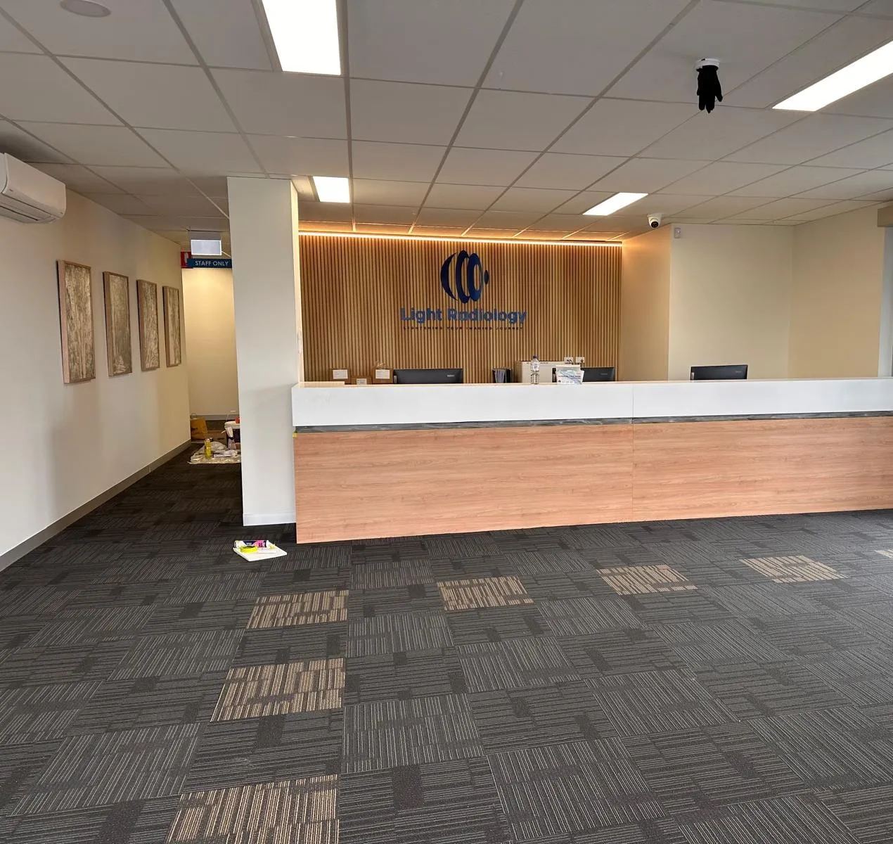 A clinic reception with a wood slat wall and a long white desk
