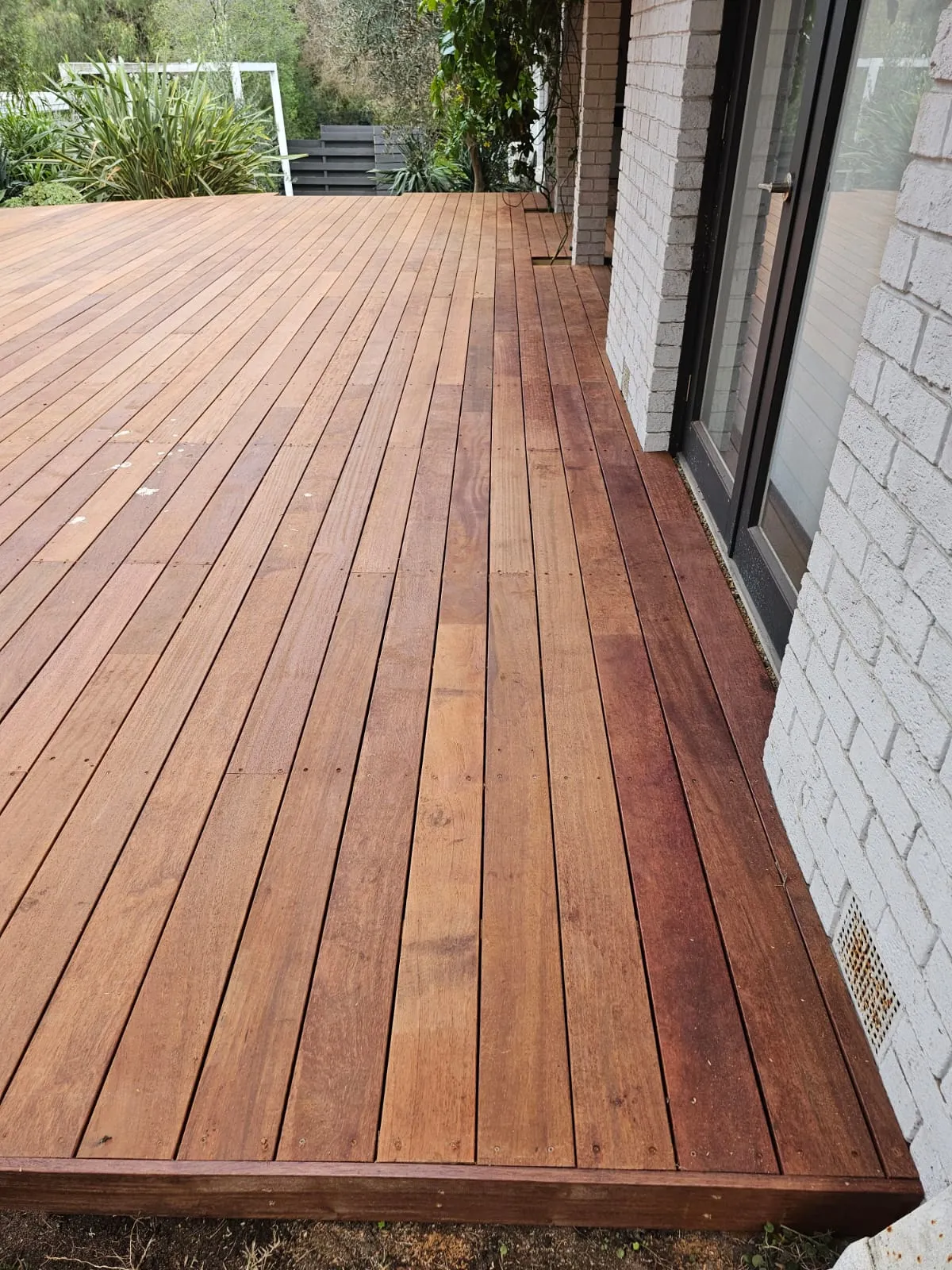 A stained wood deck along the side of a house