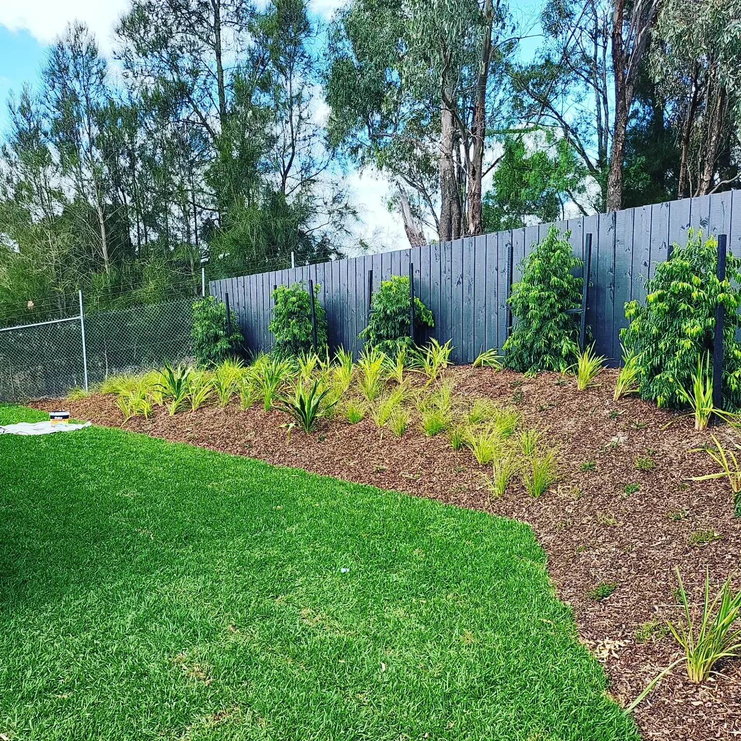 A charcoal fence along a lawn and garden bed