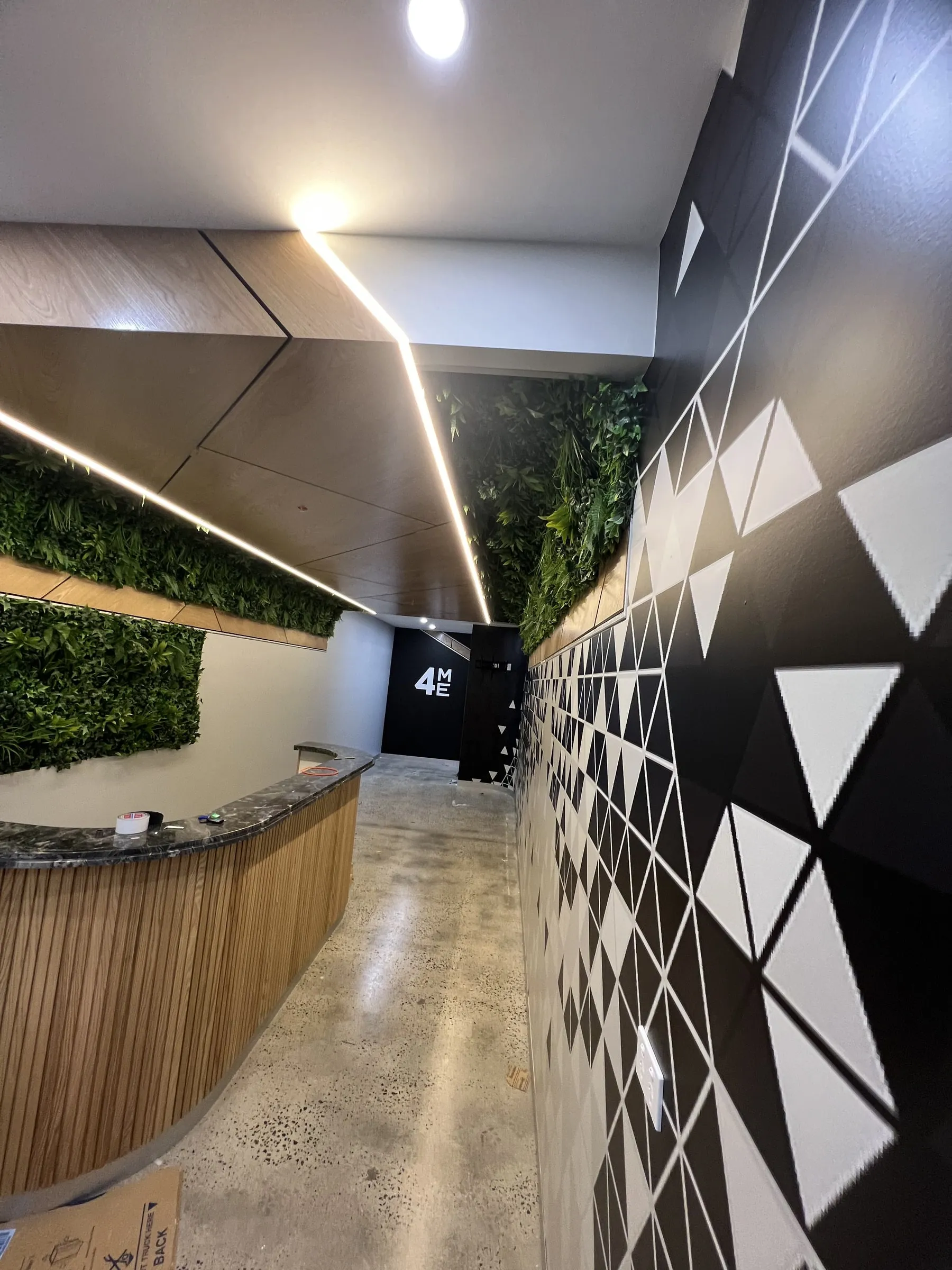 A reception with a black and white triangle-pattern feature wall beside a planted wall