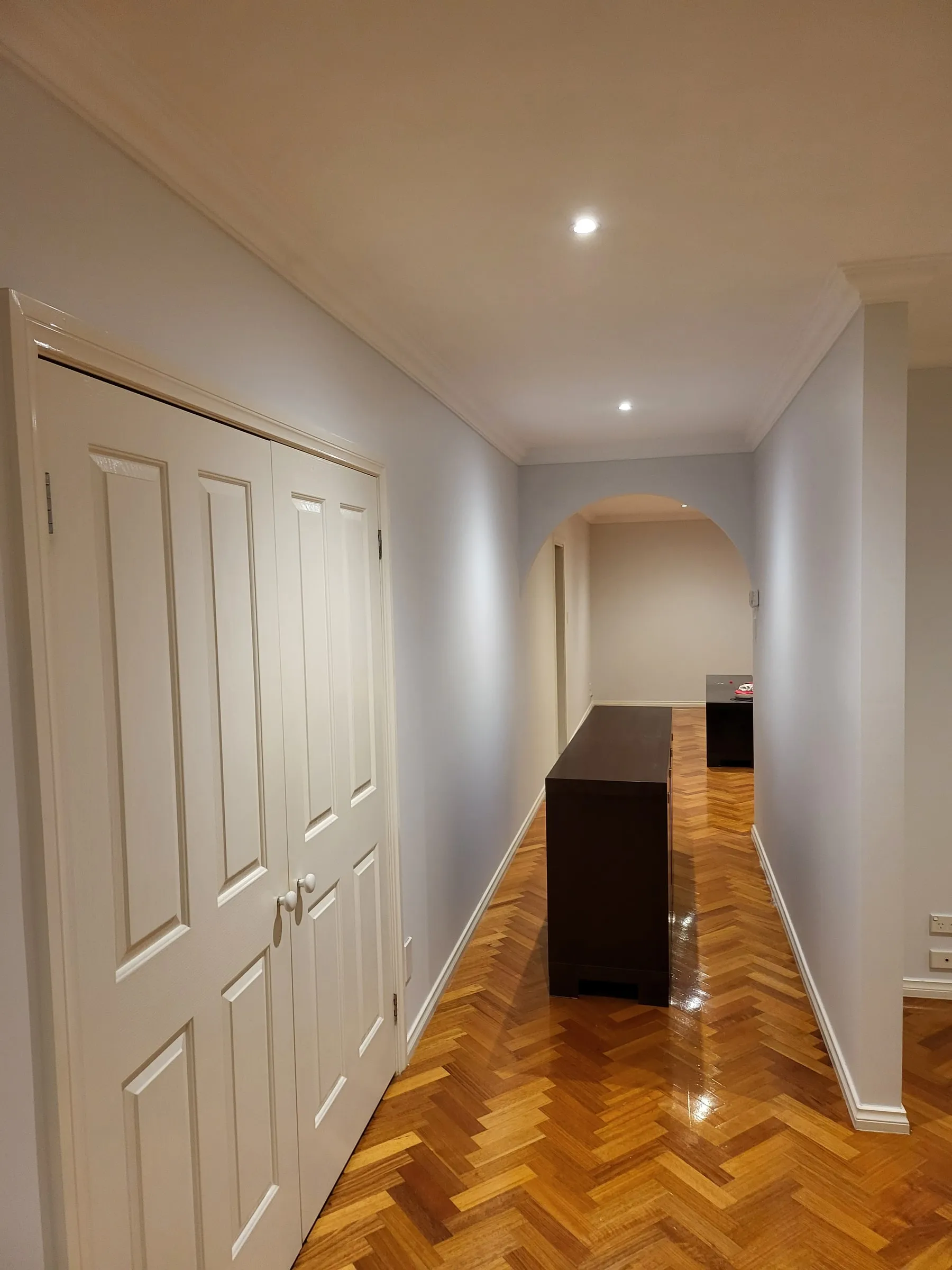 A hallway with painted walls, crown molding and double closet doors