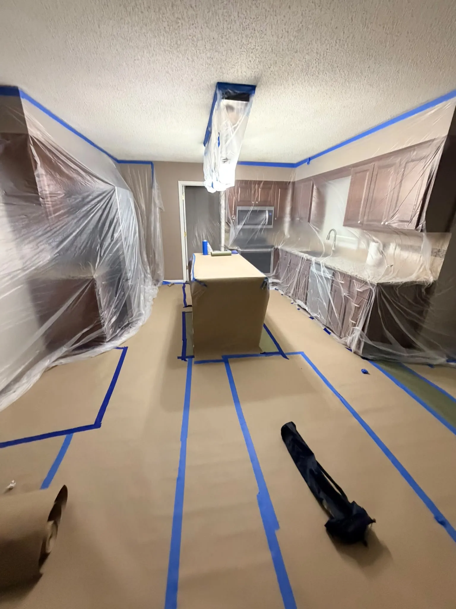A kitchen with the cabinets masked off before painting