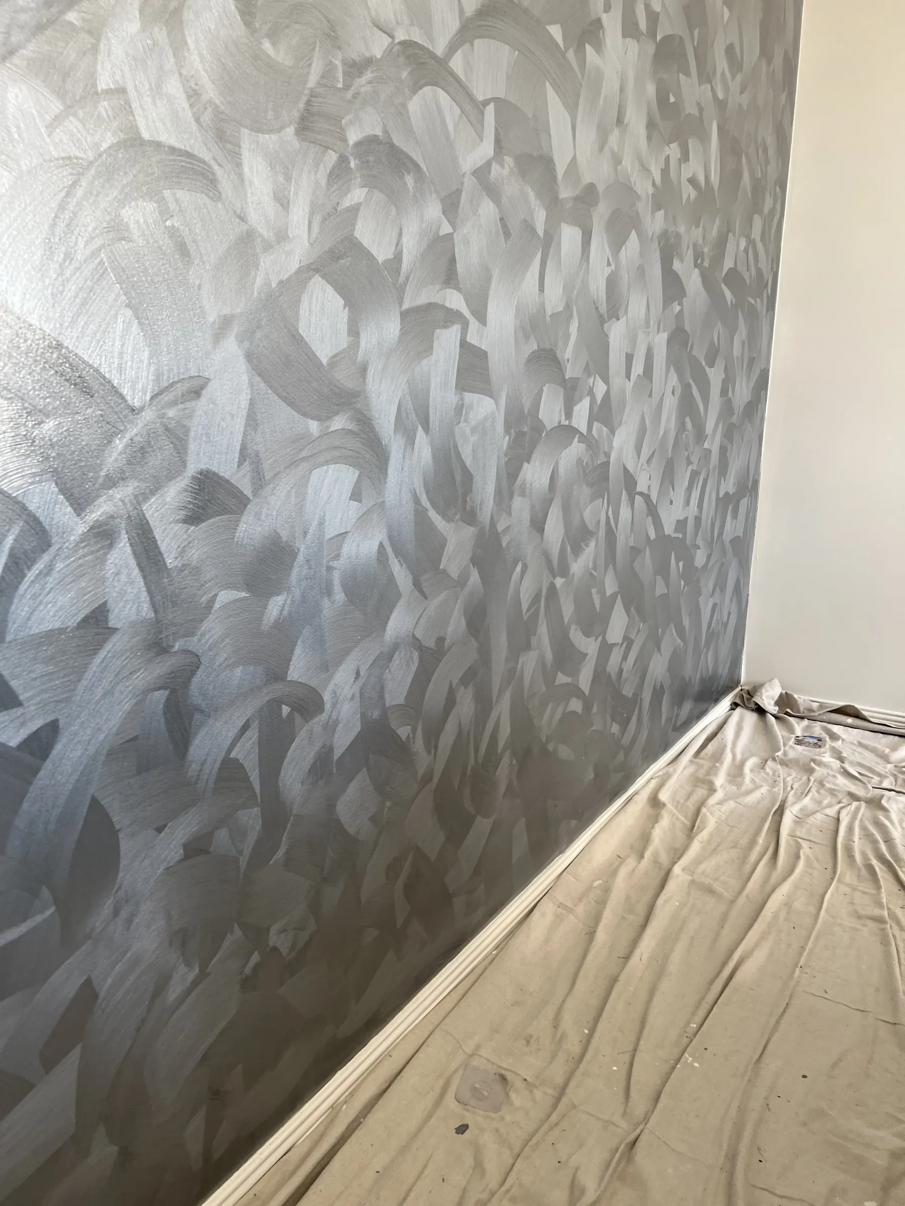 A troweled metallic feature wall above a drop cloth