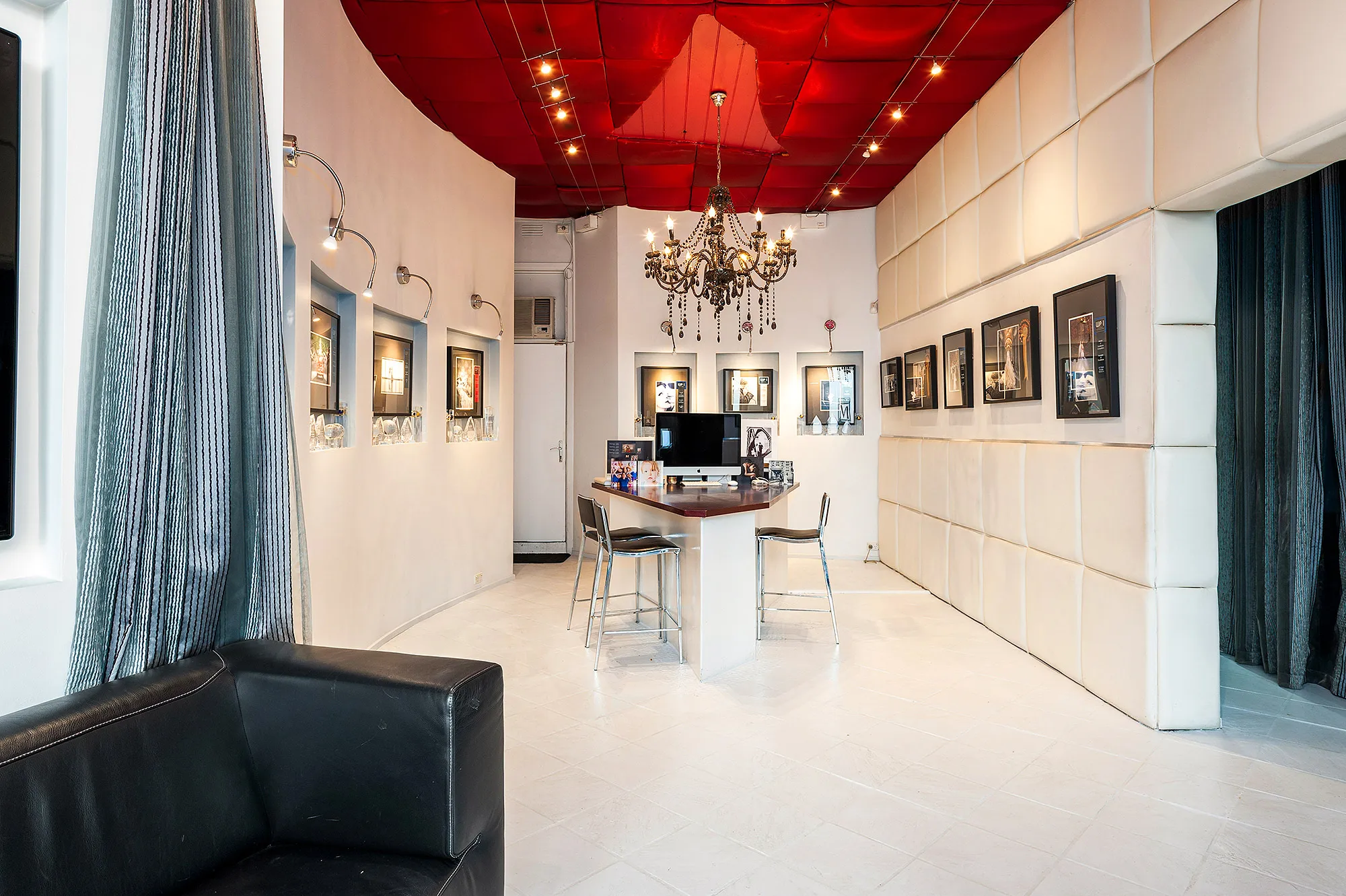 A white salon interior with a red ceiling and a chandelier