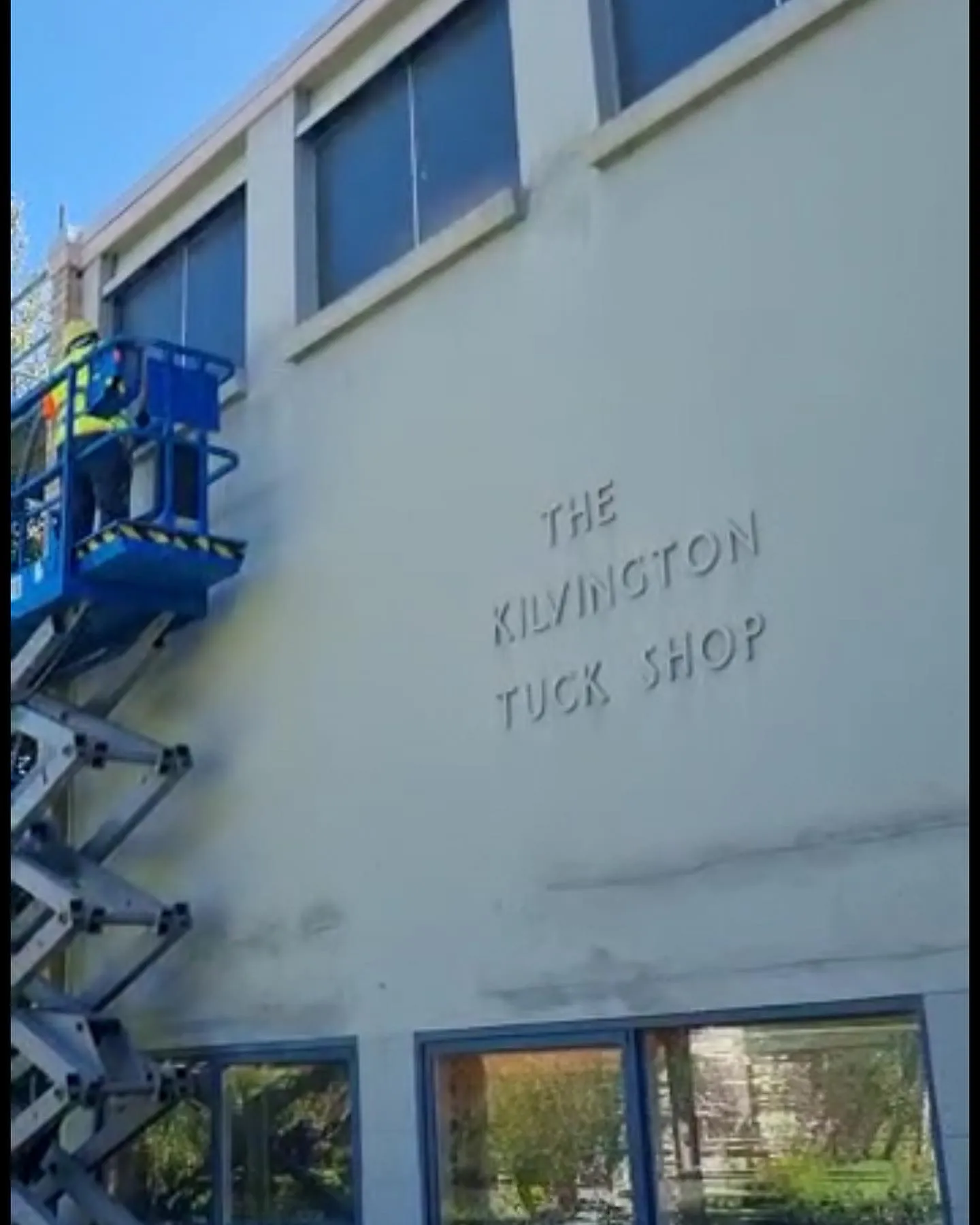 A painter on a lift at a school building wall