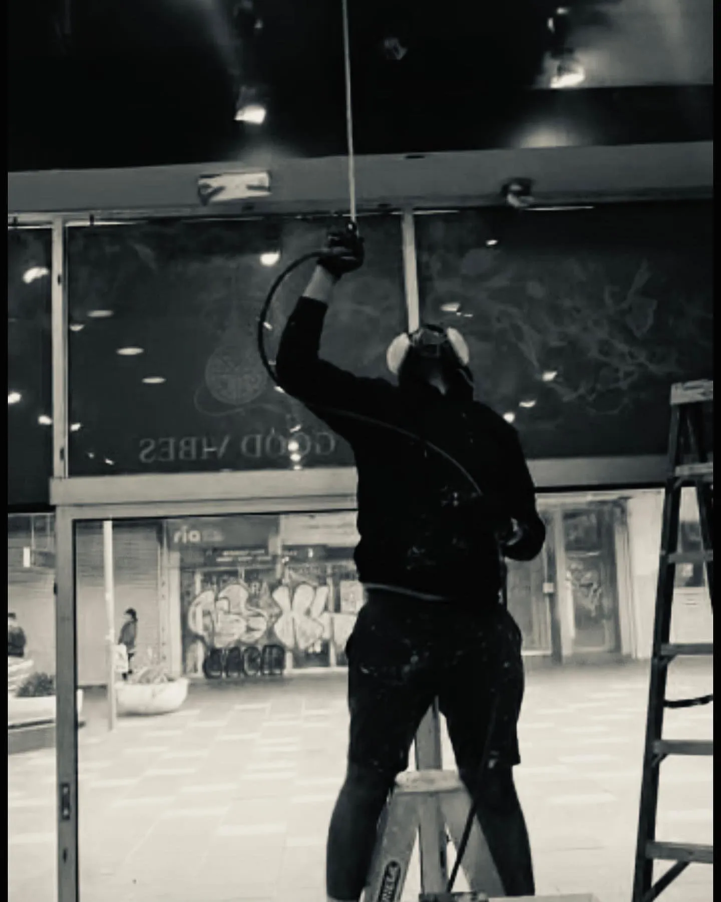 A painter on a ladder inside a dark-painted shop