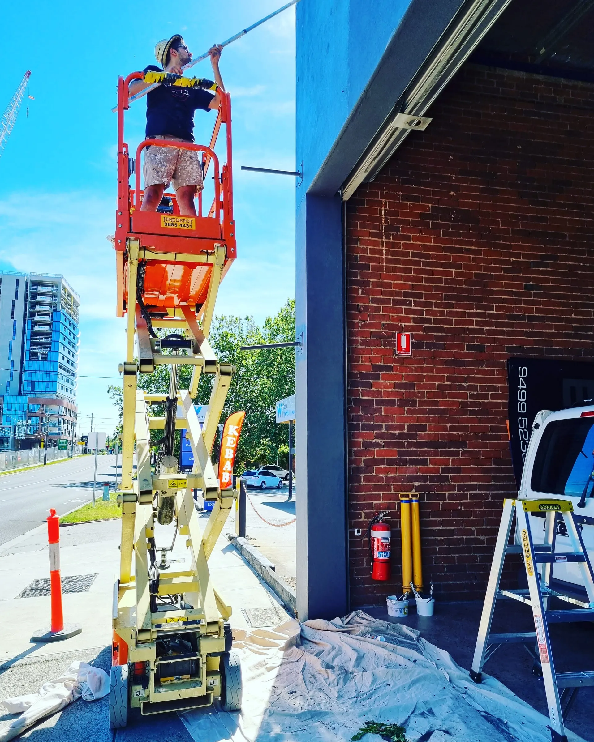 A painter on a scissor lift at a storefront