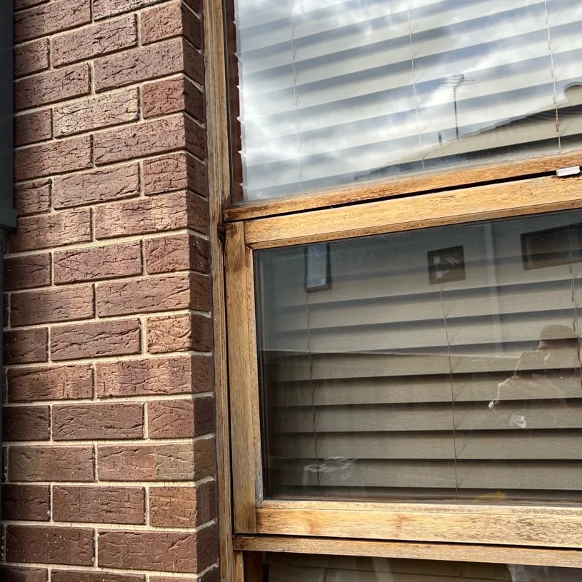 A bare wood window frame in a brick wall